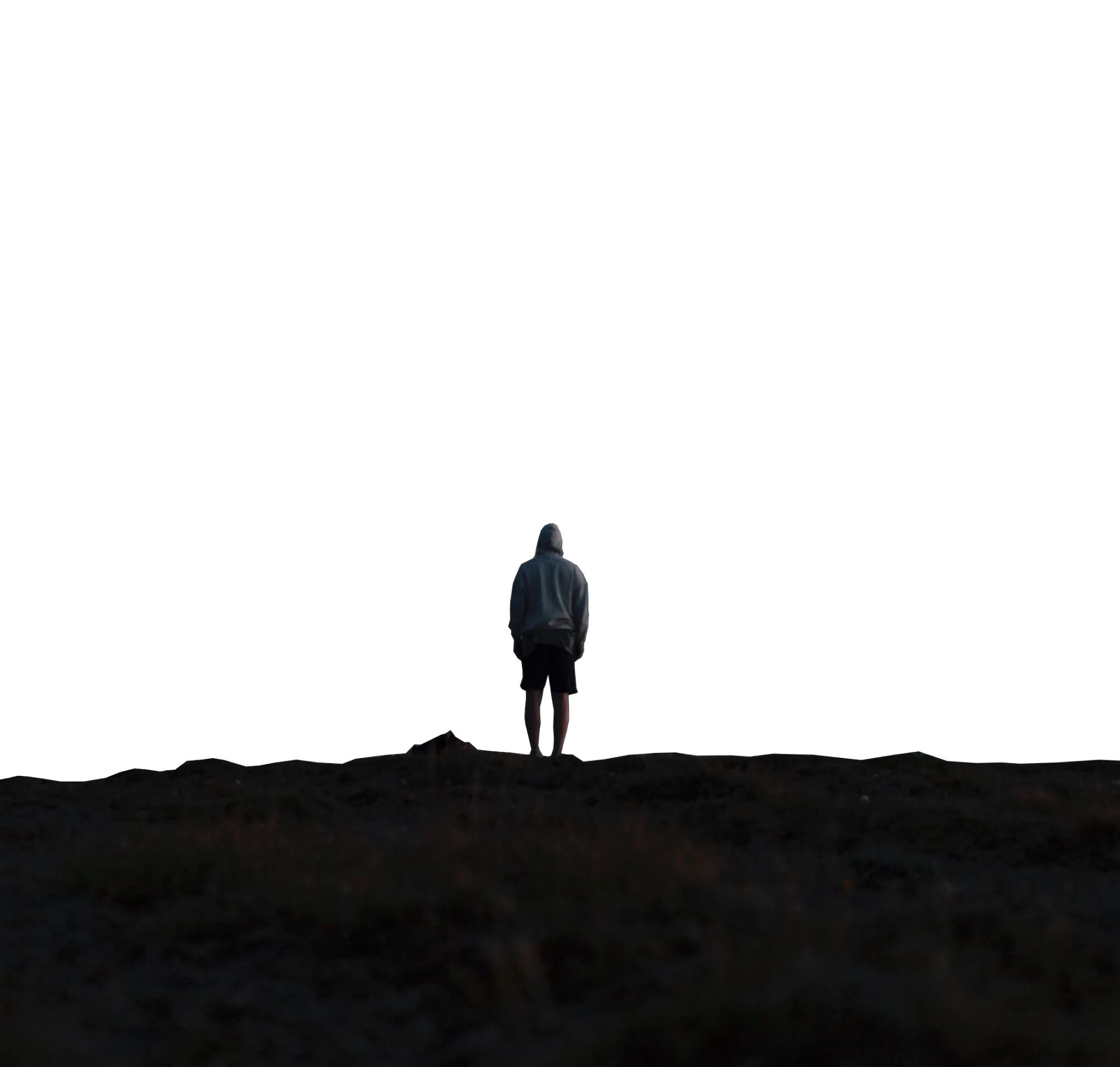 A figure in a hoodie standing before Hooiberg, Aruba.